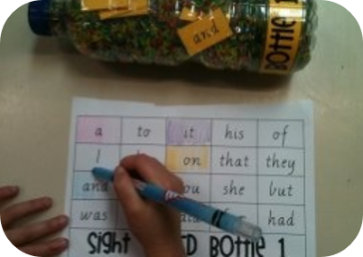 마분지나 두꺼운 도화지에 필기도구로 표를 만들고 표 안에 글자를 쓰는 모습